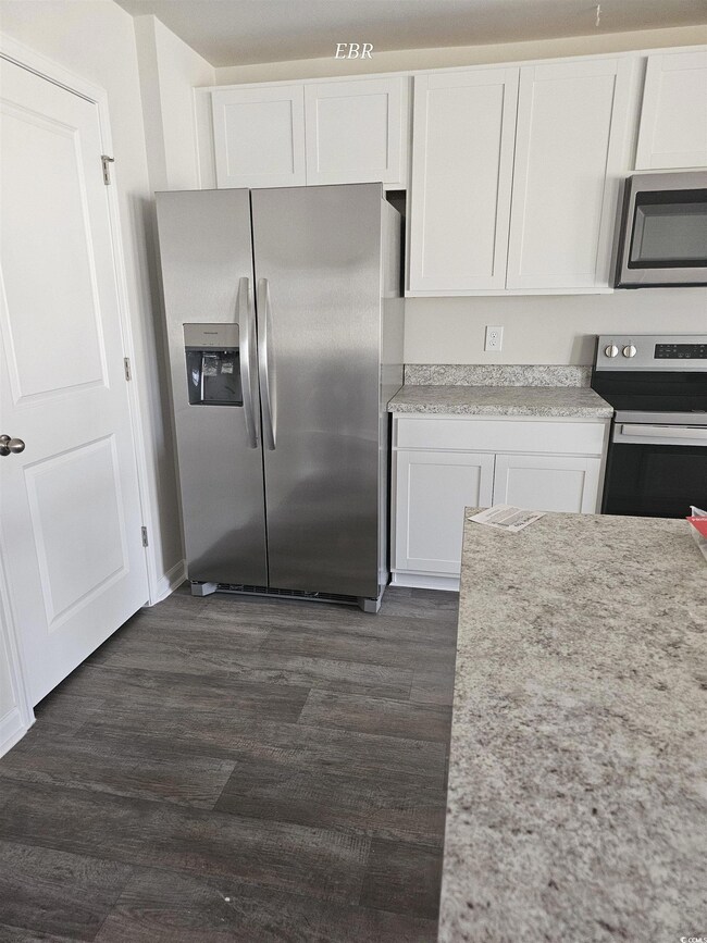 Kitchen with white cabinets, appliances with stain