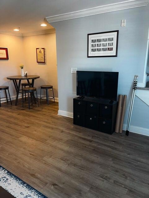 Living area with crown molding, dark wood-type fl