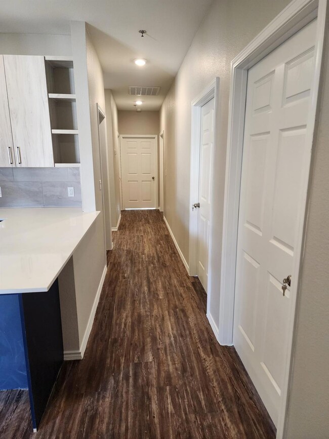 Hallway with dark wood-type flooring, baseboards,