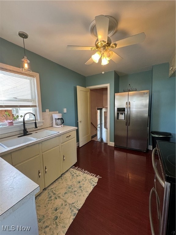 Kitchen with refrigerator, range, light countertops, pendant lighting, and dark wood finished floors