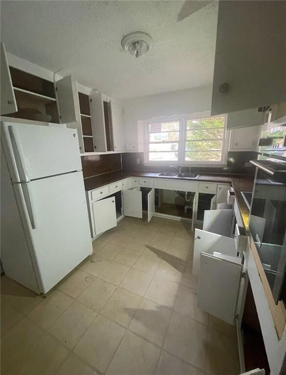 Kitchen featuring white cabinetry, white fridge, s