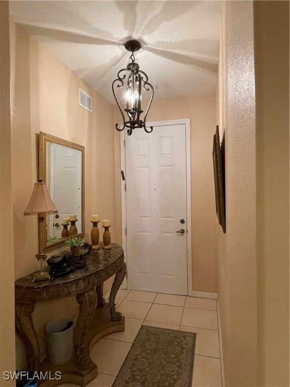 Doorway to outside with a chandelier and light til