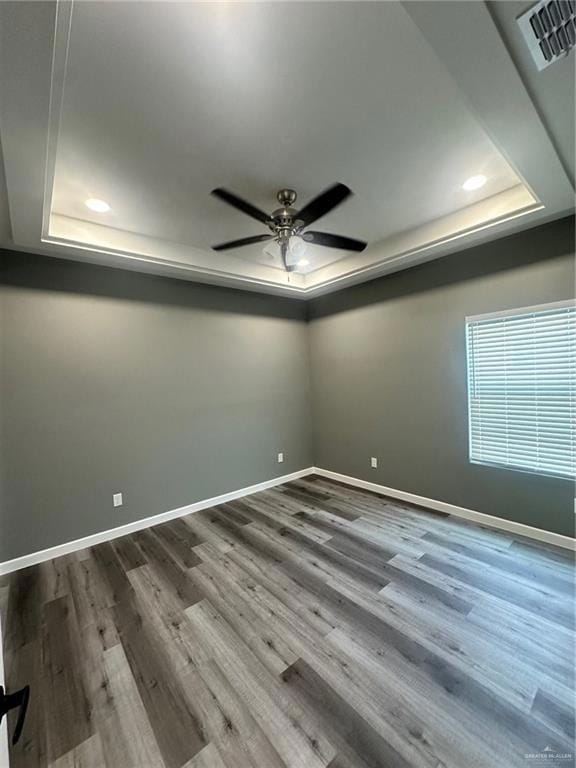 Empty room featuring a raised ceiling, recessed lighting, and ceiling fan