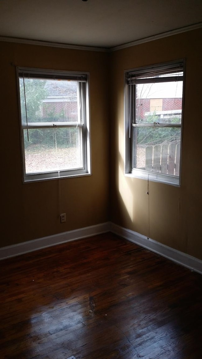 Unfurnished room with dark wood finished floors and ornamental molding