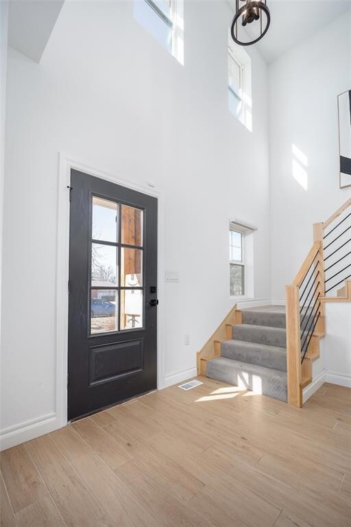 Entryway featuring a healthy amount of sunlight, visible vents, light wood finished floors, and stairs