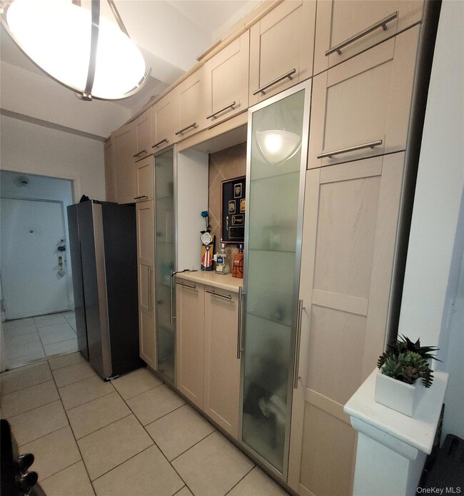 Kitchen with light tile patterned flooring, light countertops, and freestanding refrigerator