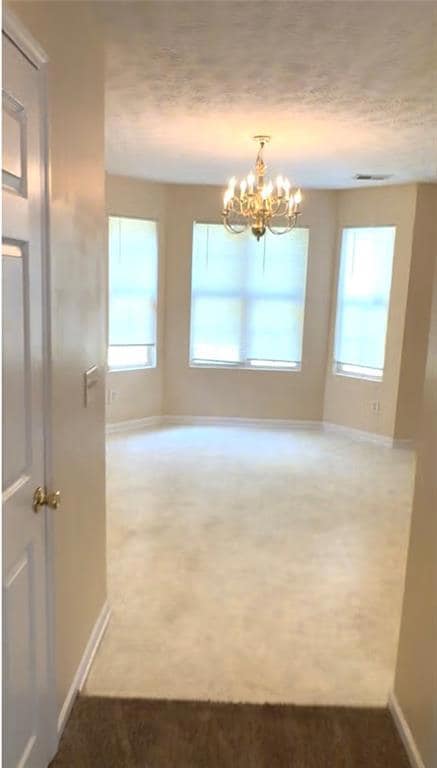 Unfurnished dining area featuring carpet floors and a chandelier