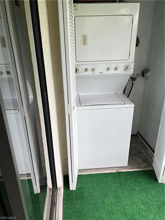 Laundry area with stacked washer and clothes dryer and a textured wall