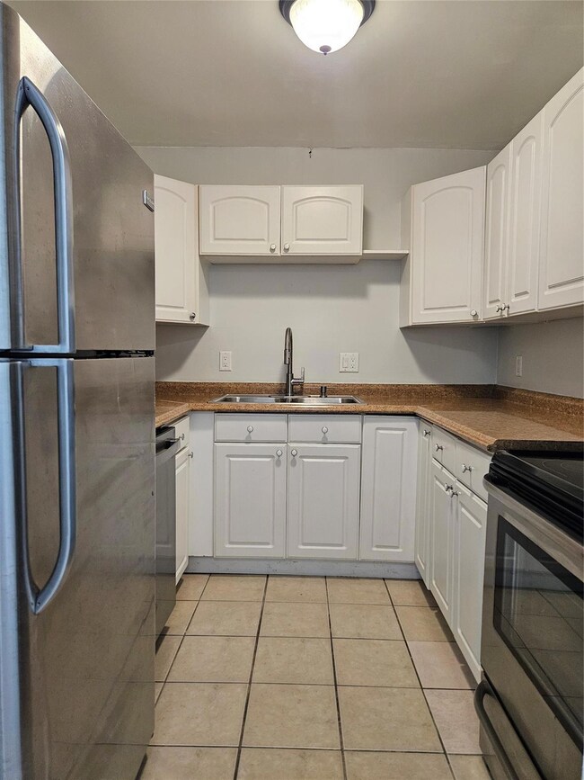 Kitchen features white cabinets, stainless steel a