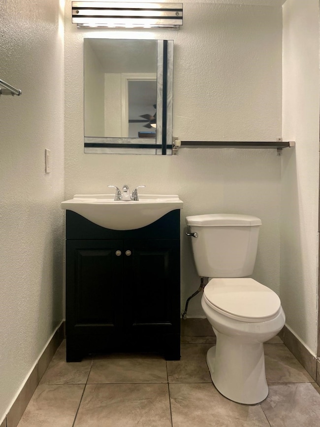 Bathroom featuring a textured wall, vanity, and light tile patterned flooring