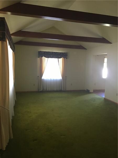 Living room with vaulted ceiling and wood beams.
