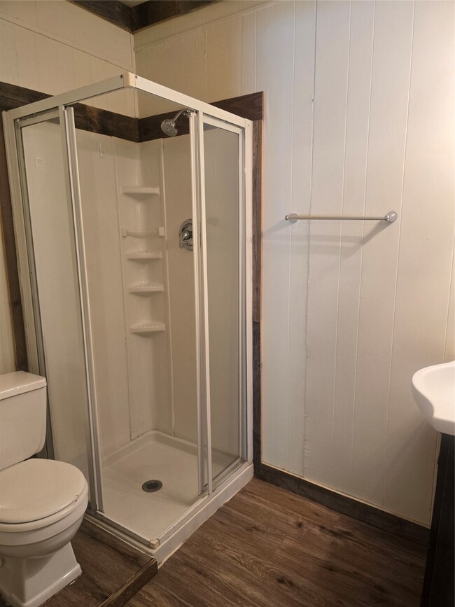 Bathroom with dark wood-type flooring and a stall shower