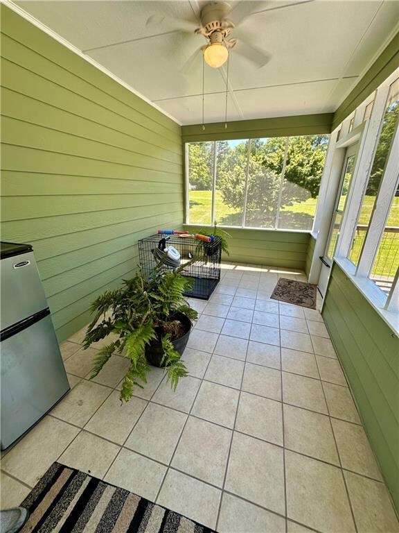 Unfurnished sunroom with ceiling fan and plenty of