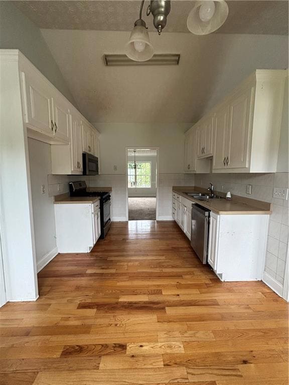 Kitchen featuring range, dishwashing machine, lofted ceiling, and light wood-style floors