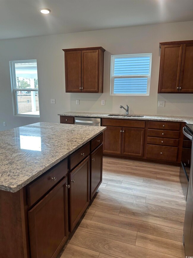 Kitchen featuring stove, light stone counters, sin