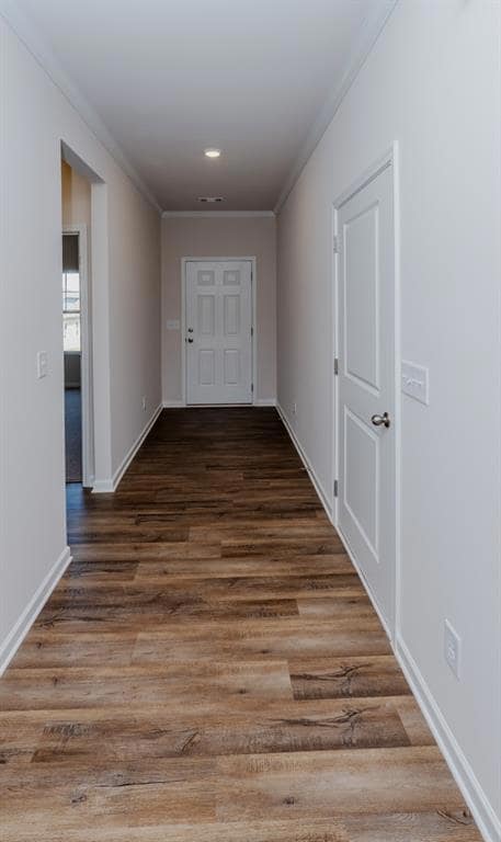 Hall with ornamental molding, wood finished floors, and baseboards