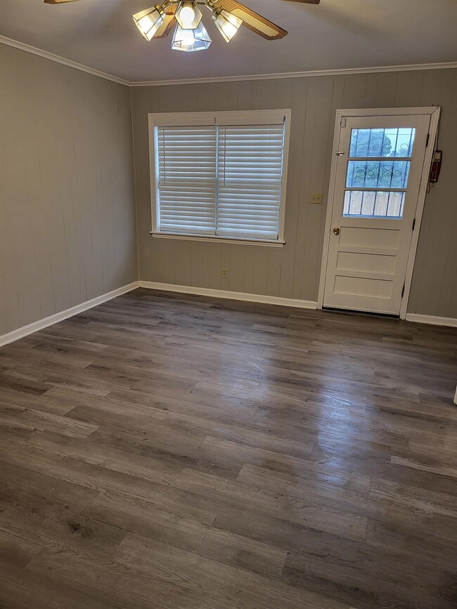 Den featuring ceiling fan, crown molding, and dark