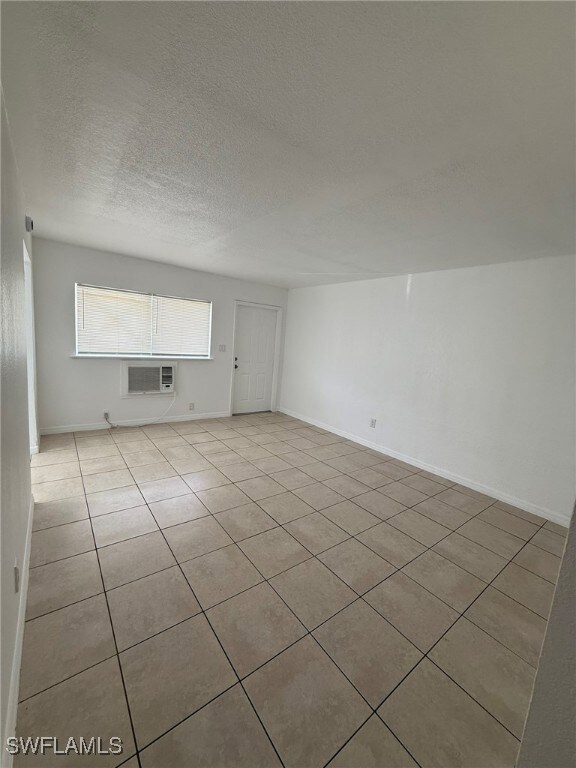 Tiled empty room with a textured ceiling and an AC