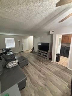 Living room featuring a textured ceiling, light wood-type flooring, and ceiling fan