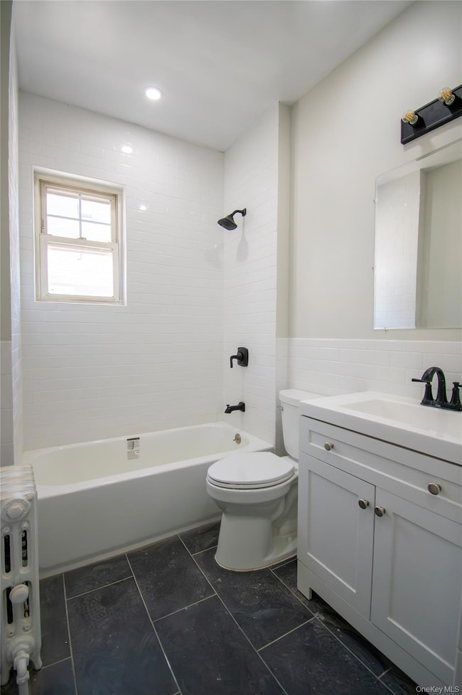 Bathroom featuring radiator heating unit, vanity, and  shower combination