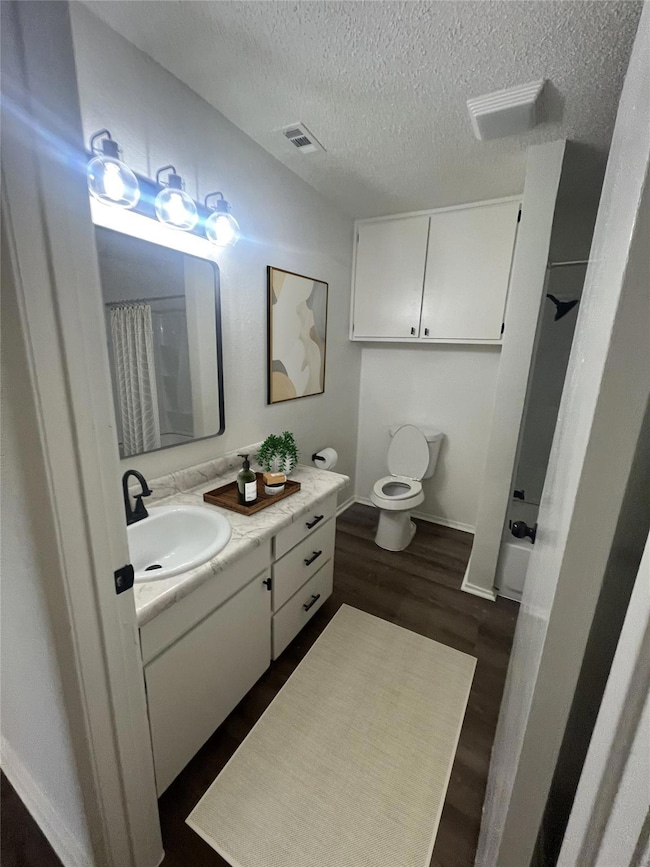 Bathroom with toilet, a textured ceiling, vanity, 