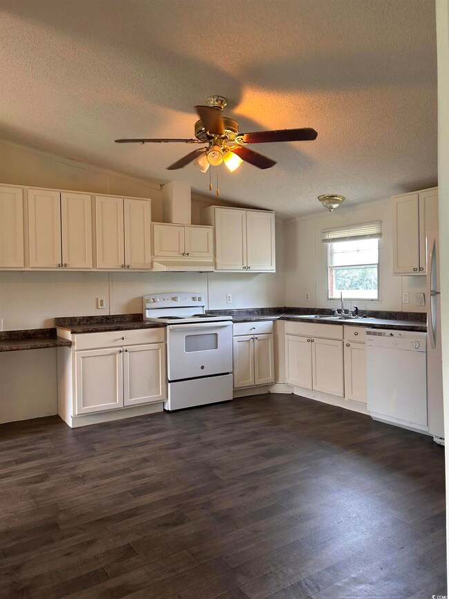 Kitchen with ceiling fan, dark wood-type flooring,