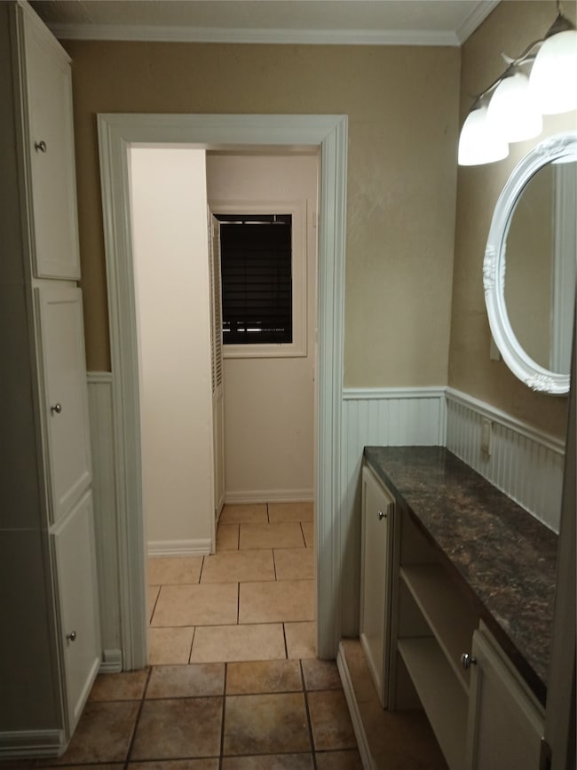 Bathroom with crown molding, light tile patterned flooring, a wainscoted wall, and vanity
