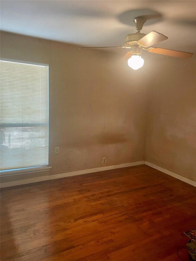 Unfurnished room featuring ceiling fan and dark ha