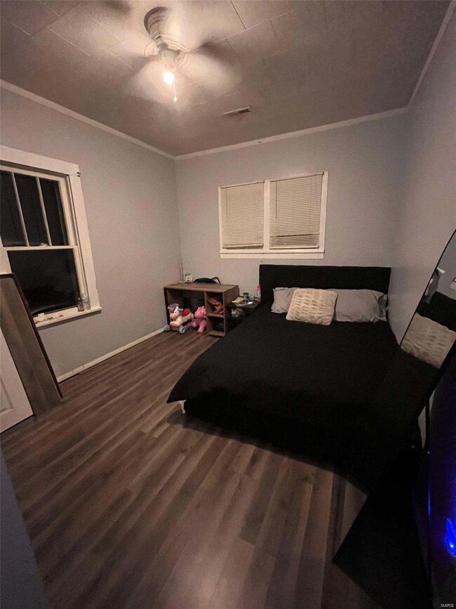 Bedroom featuring dark hardwood / wood-style flooring, ornamental molding, and ceiling fan