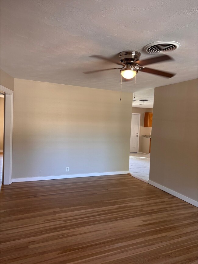 Spare room featuring wood finished floors, ceiling fan, and a textured ceiling
