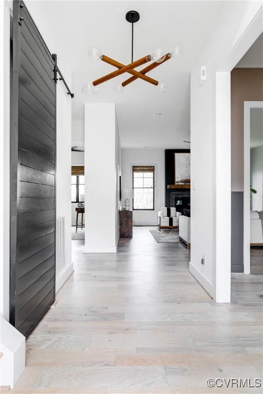 Hallway with a barn door, light hardwood / wood-st