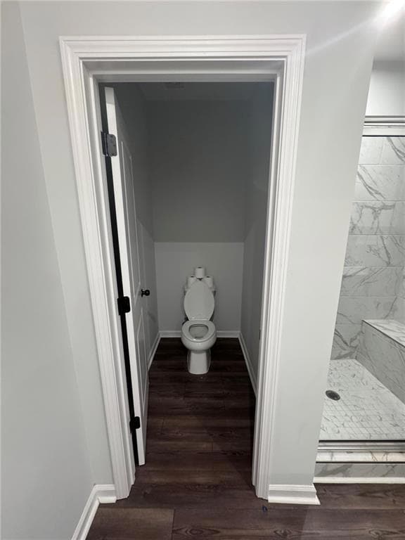 Bathroom featuring dark wood-style floors and a marble finish shower