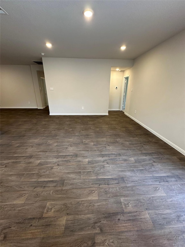 Spare room featuring baseboards, dark wood finish