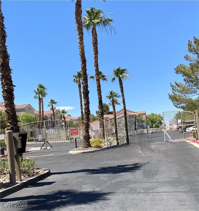 View of asphalt road featuring a gate, a gated ent