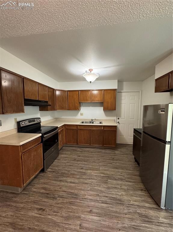 Kitchen with fridge, stove, exhaust hood, a sink, and dark wood finished floors