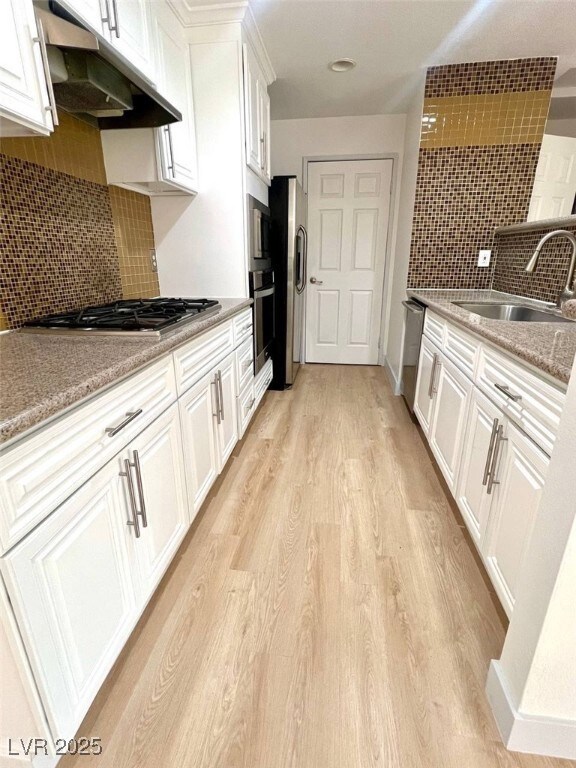 Kitchen with white cabinets, a sink, stainless ste