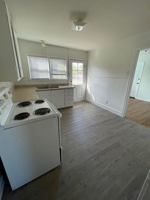 Kitchen featuring electric range, white cabinets, light countertops, wood finished floors, and wainscoting