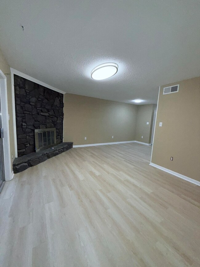 Unfurnished living room with a stone fireplace, wo