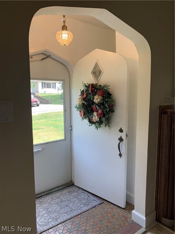 Doorway with lofted ceiling and tile patterned floors