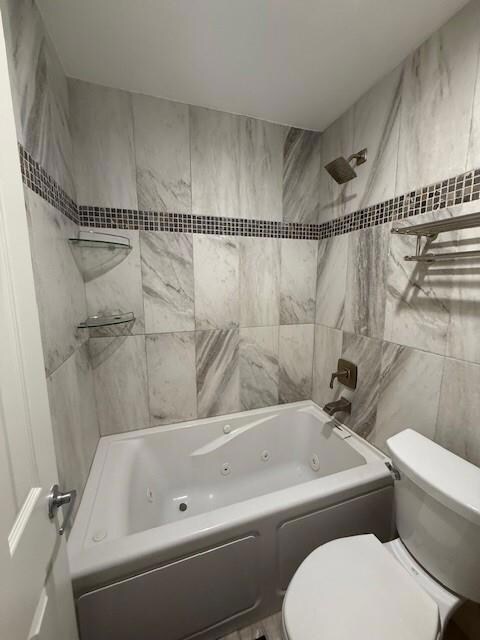 Bathroom featuring toilet and tiled shower / bath 