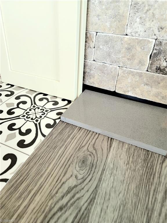 Cream cabinets, stone tile backsplash, grey quartz counter, grey wood vinyl flooring and medallion vinyl flooring in baths