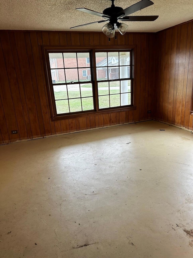 Spare room with wooden walls, a textured ceiling, 