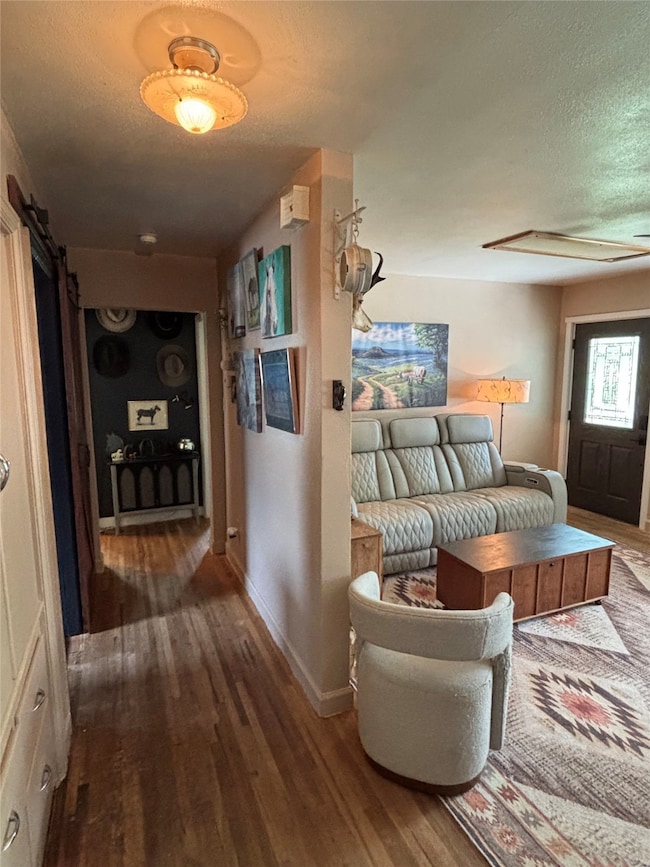 Hallway featuring a textured ceiling, a barn door, and dark wood-style flooring