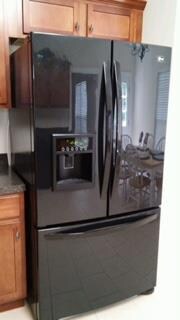 beautiful black side by side refrigerator with Ice maker in the door.   staying!!!
