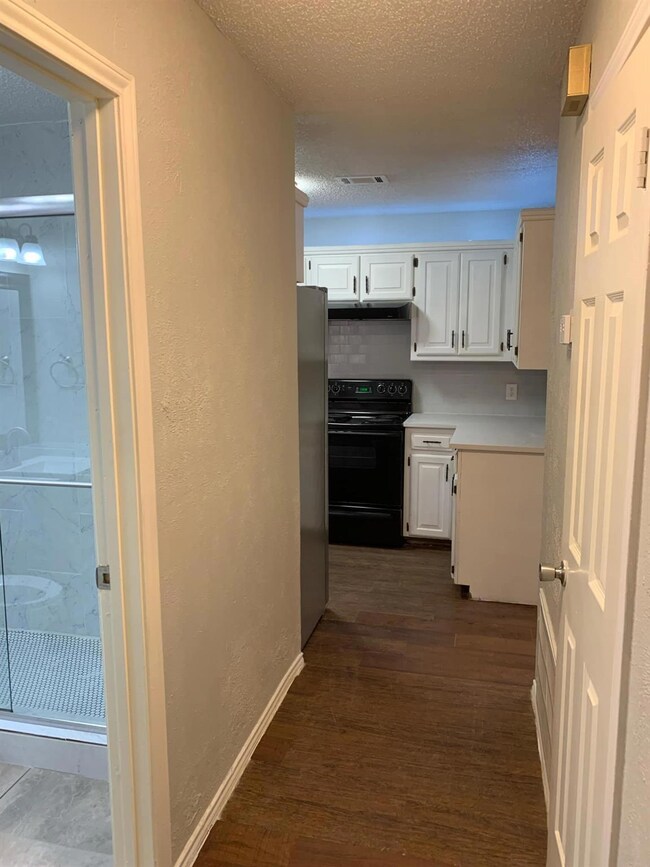 Hall with a textured ceiling and dark wood-type flooring