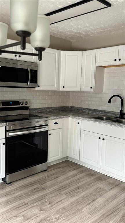 Kitchen featuring a sink, white cabinetry, backsplash, and stainless steel appliances