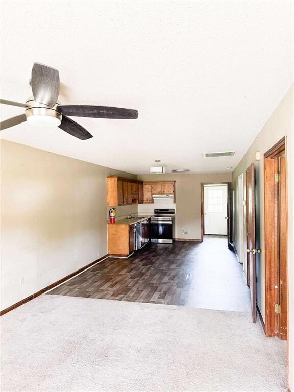 Unfurnished living room with dark colored carpet, baseboards, a sink, and ceiling fan