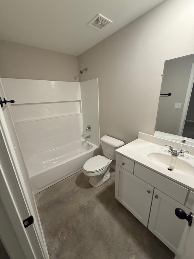 Full bathroom with toilet, vanity, concrete flooring, and shower / washtub combination
