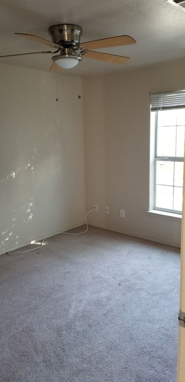 Empty room with carpet floors and ceiling fan