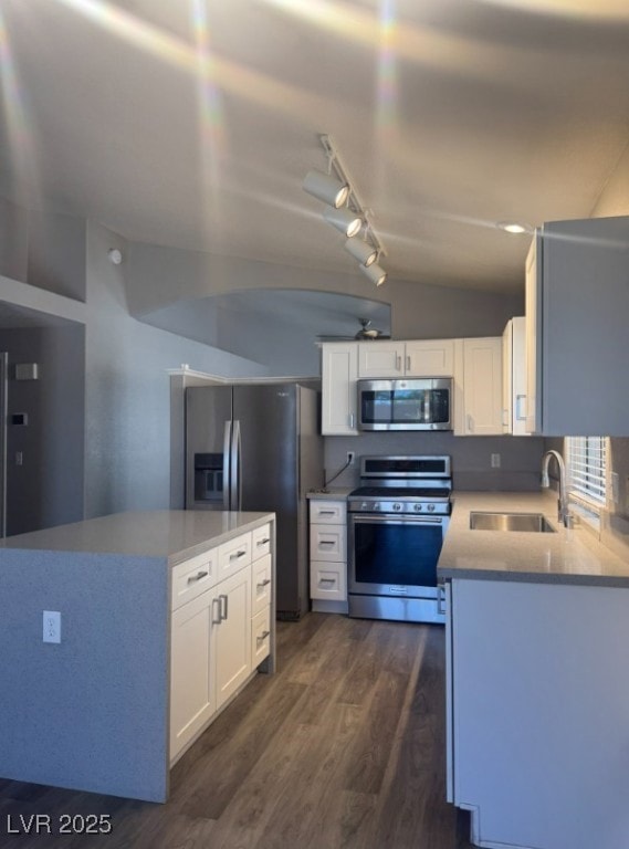 Kitchen featuring appliances with stainless steel finishes, light stone countertops, white cabinets, dark wood-style flooring, and rail lighting